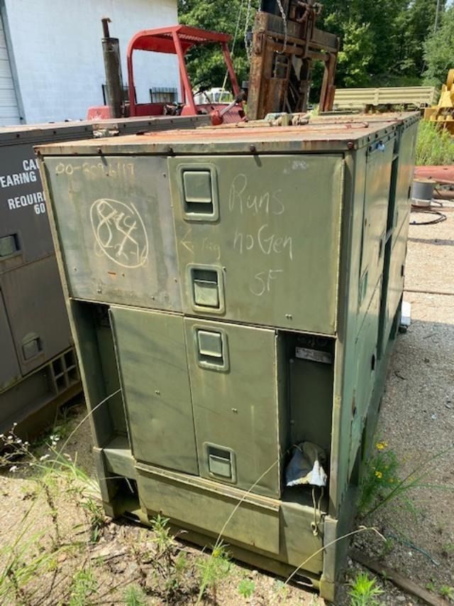 A green metal box is sitting in the dirt next to a forklift.