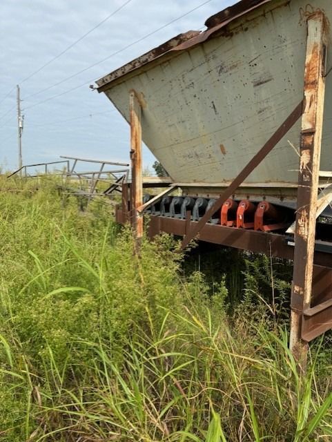A large white container is sitting in a field of tall grass
