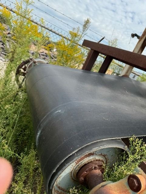 A large black pipe is sitting in the grass.