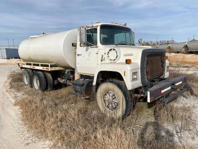 A white truck is parked on the side of a dirt road.