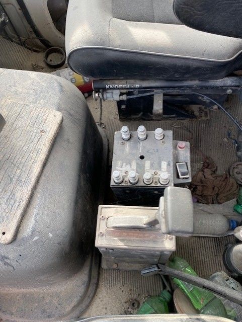A battery is sitting on the floor of a vehicle next to a seat.