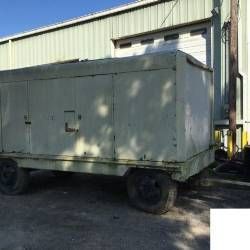 A large white trailer is parked in front of a building.