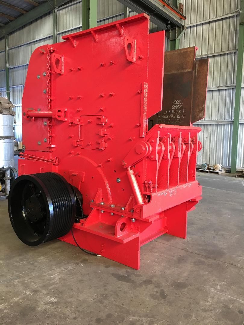 A large red machine is sitting in a warehouse.