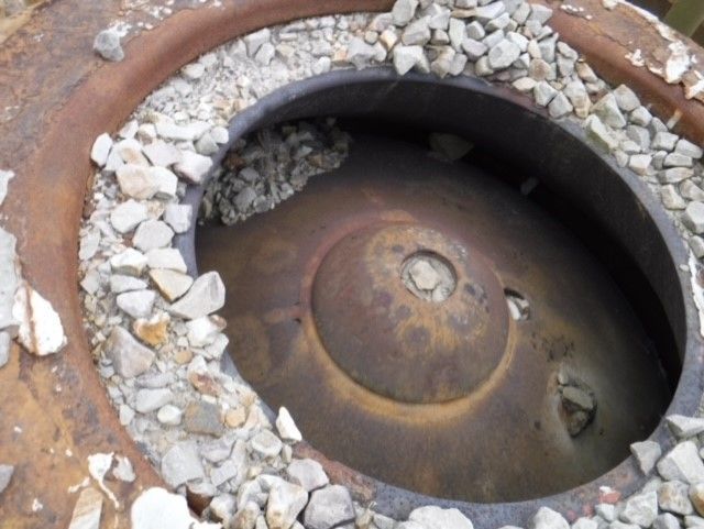 A hole in a metal object surrounded by rocks