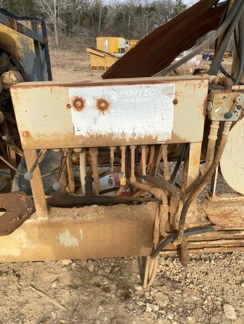 A rusty machine is sitting in the dirt in a field.