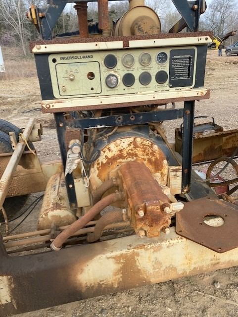 An old rusty machine is sitting in the dirt in a field.