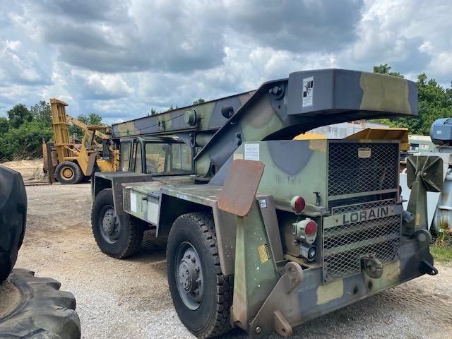 A large military vehicle is parked in a gravel lot.