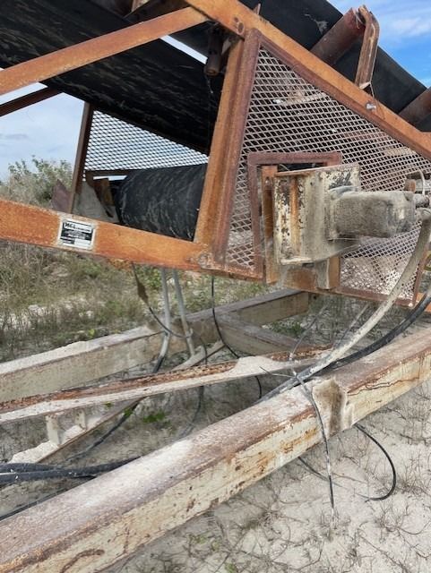 A rusty metal structure with a conveyor belt attached to it