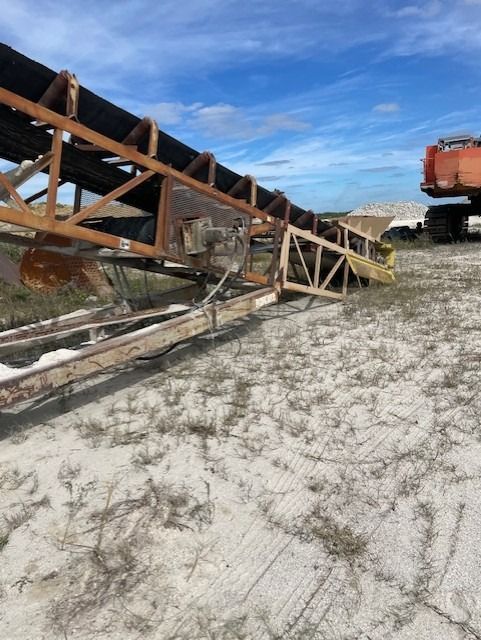 A conveyor belt is sitting in the middle of a dirt field