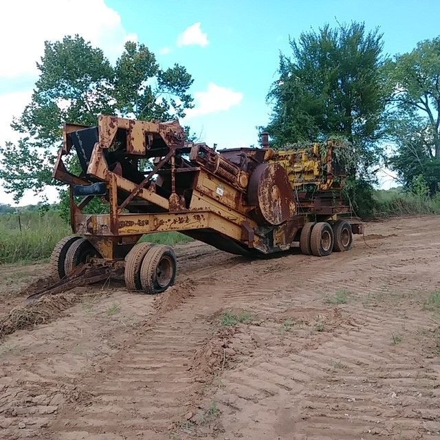 An old rusty tractor is parked in a dirt field