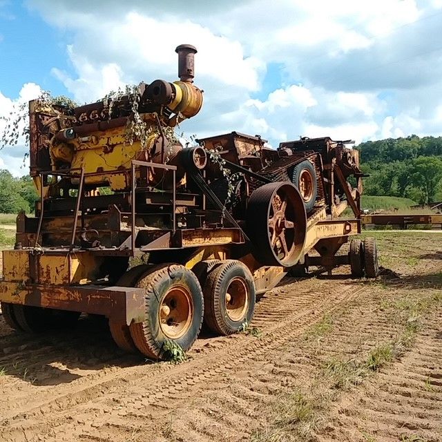 An old rusty tractor is parked in a dirt field