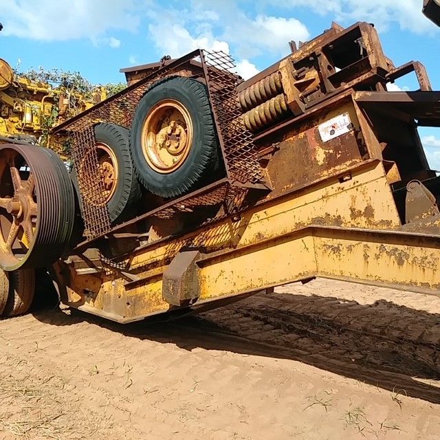 A yellow tractor is laying on its side in the dirt.