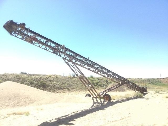 A conveyor belt is sitting in the middle of a dirt field