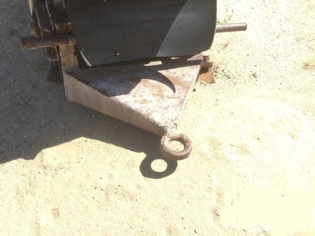 A metal object with a hook attached to it is sitting on the ground.