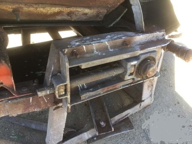 A rusty piece of metal is sitting on the ground next to a car.