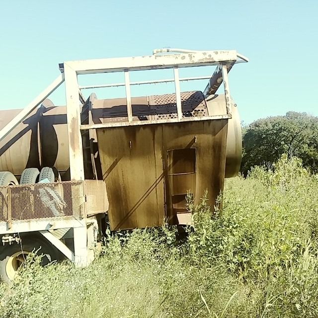 A building with a balcony is surrounded by tall grass