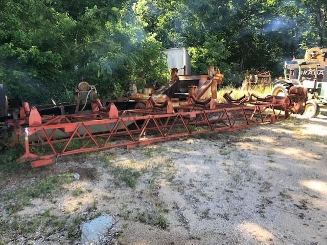 A bunch of old tractors are parked in a dirt lot.