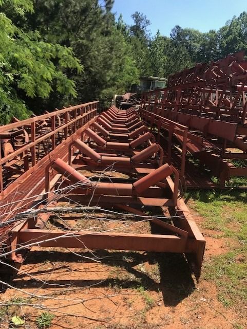 A row of conveyor belts are sitting in the dirt