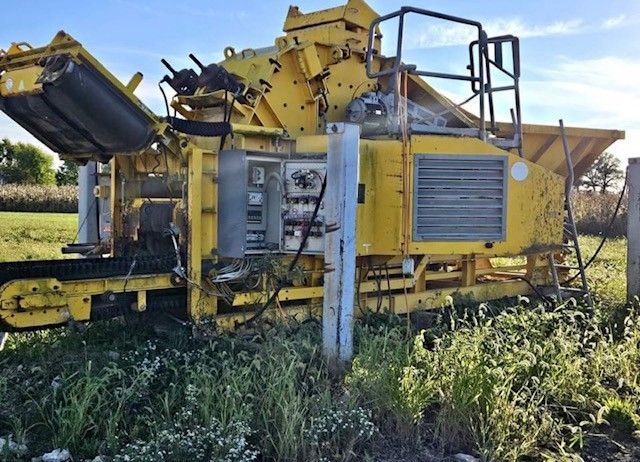 A large yellow machine is sitting in the middle of a grassy field