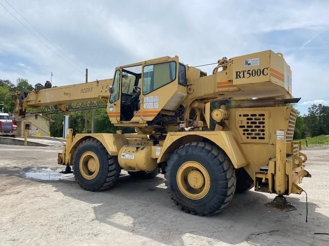 A large yellow crane is parked in a dirt lot.
