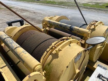A large yellow winch is sitting on the side of the road.