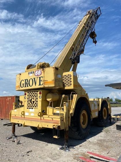 A yellow grove truck is parked in a gravel lot