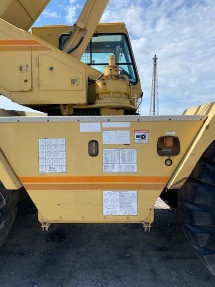 A yellow tractor with a large tire is parked in a parking lot