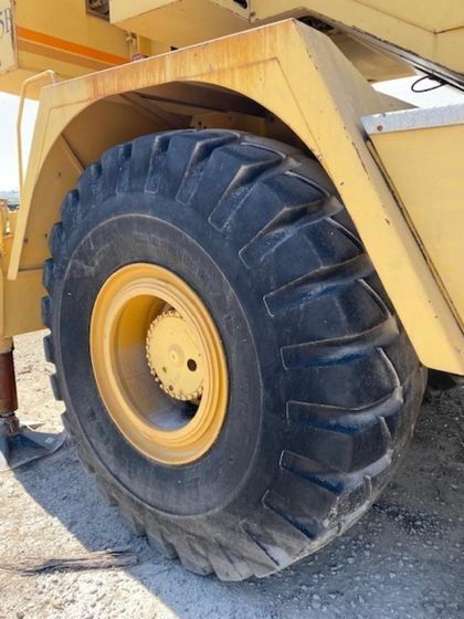 A close up of a large tire on a yellow vehicle