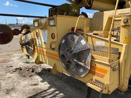 A large yellow tractor is parked in a dirt field.