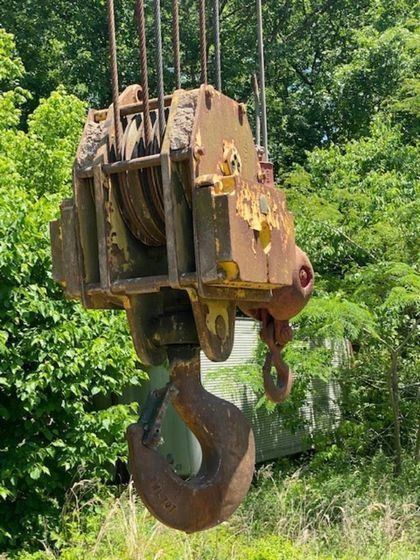 A large hook is hanging from a crane in a field.