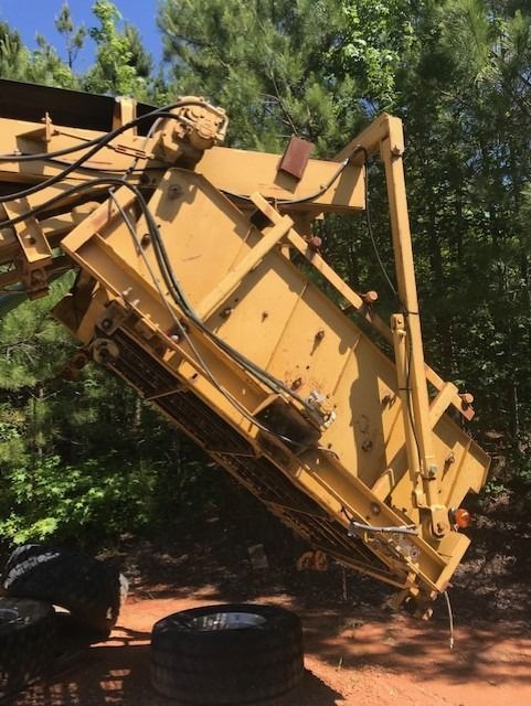 A large yellow machine is sitting on a dirt road