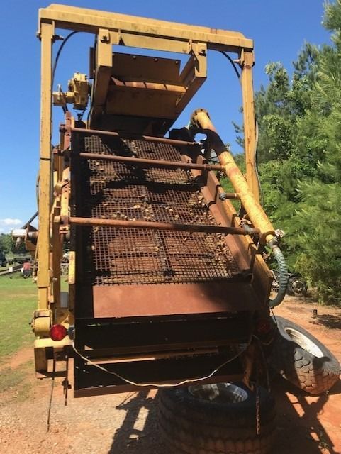 A large machine is sitting in the dirt with trees in the background