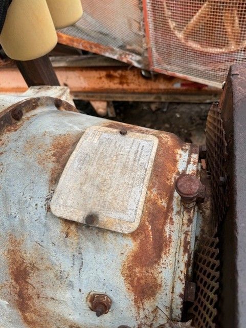A close up of a rusty engine with a label on it.
