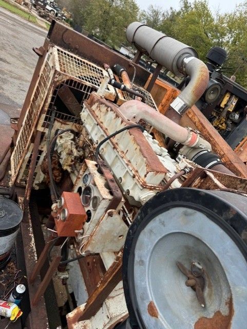 A rusty engine is sitting on the ground in a parking lot