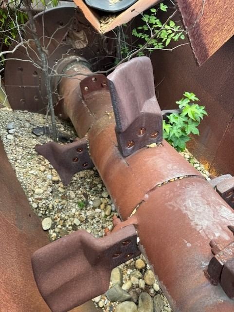 A rusty pipe is sitting in a pile of rocks