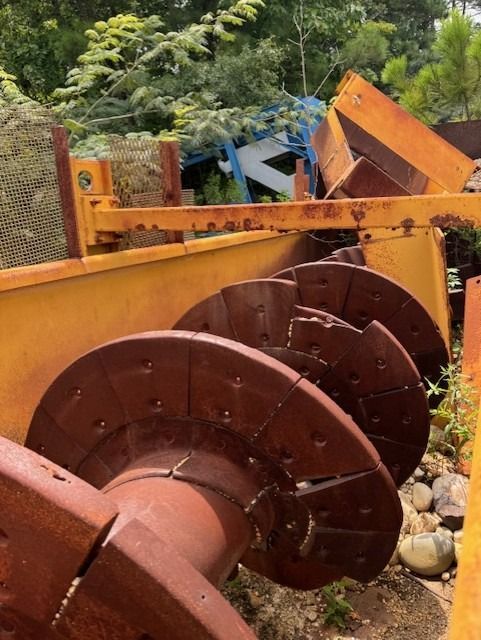 A bunch of rusty metal spools are sitting on the ground