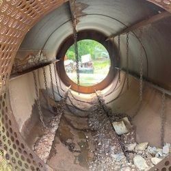 The inside of a large metal pipe with a hole in the middle.