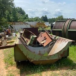 A pile of rusty metal is sitting in the grass in a field.
