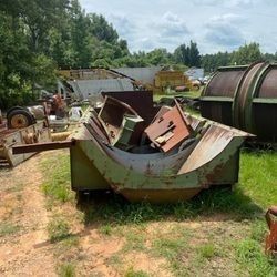 A pile of rusty metal is sitting in the grass in a field.