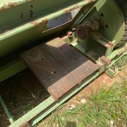 A green machine is sitting on top of a grass covered field.