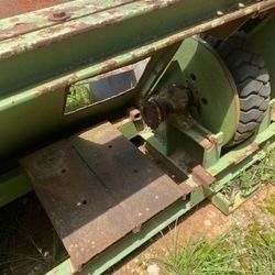 A green machine with a tire on it is sitting in the grass.