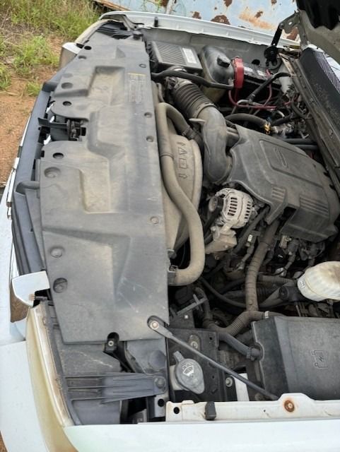 The hood of a white truck is open showing the engine