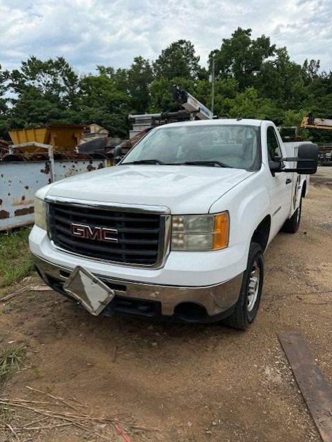 A white gmc truck is parked on a dirt road.