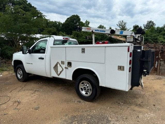 A white utility truck is parked in a dirt field.