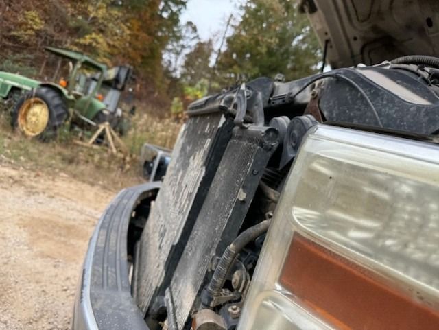 A tractor is parked behind a truck with the hood open.