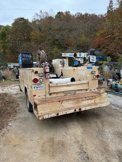 A utility truck is parked on the side of a dirt road.