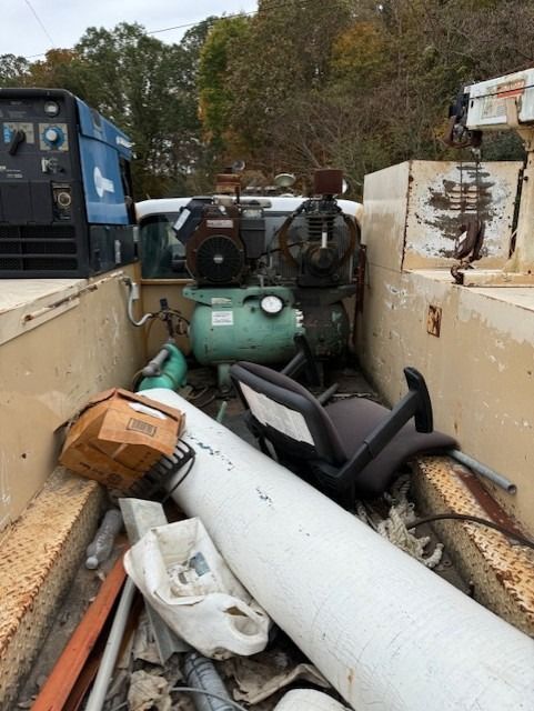 A truck filled with a lot of junk including air compressors