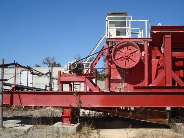 A large red machine is sitting in the dirt with a blue sky in the background