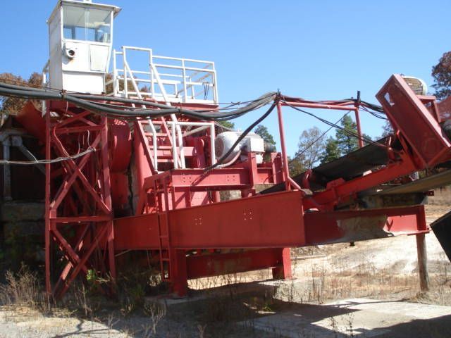 A large red and white machine is sitting in a field