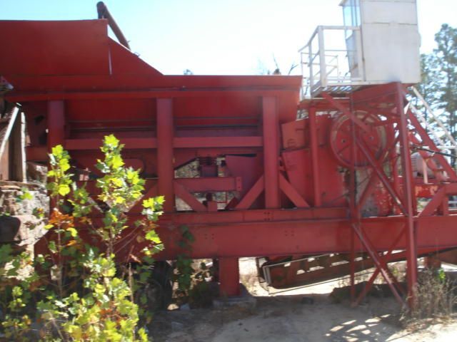 A large red machine is parked in the dirt